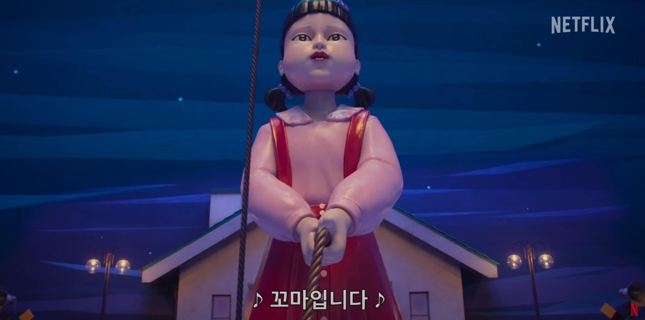 Squid Game Season 3 trailer shows the giant doll, Young-hee, under a blue night sky.