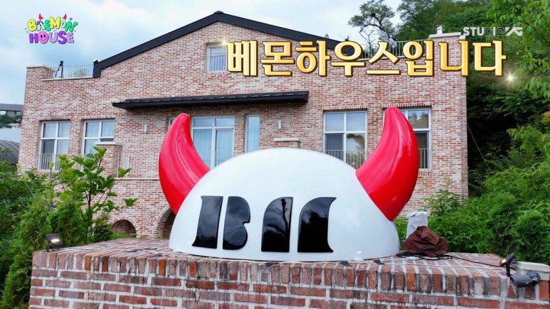 Exterior of BAEMON HOUSE with red devil horns and BABYMONSTER logo, featured in BABYMONSTER reality show