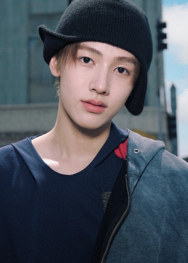 HYBE new boy group CORTIS member in plaid pants, hoodie and black beanie leaning against a street lamp in downtown.