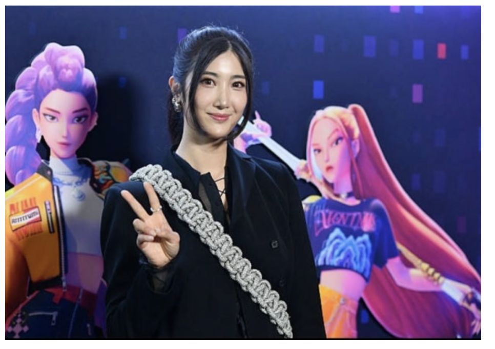 Actress posing with life-size KPop Demon Hunters Netflix character cutouts at promotional event