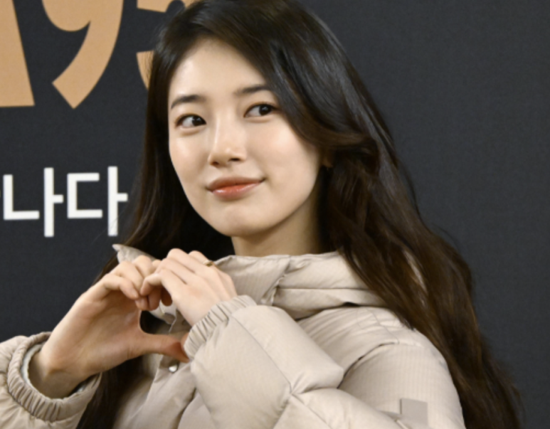 Suzy making heart gesture in beige jacket during Suzy marriage rumor period