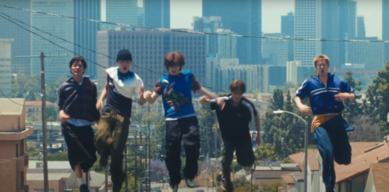 Even mid-run, Martin CORTIS height is visually dominant as the group chases a car in L.A.