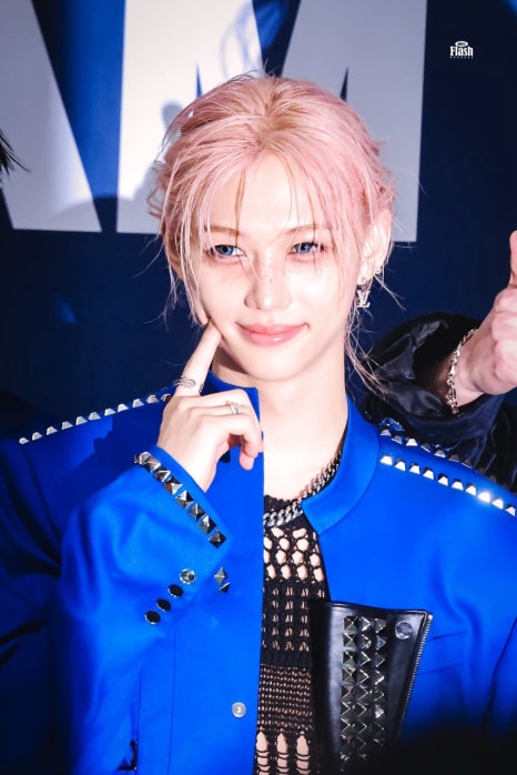 Stray Kids member in blue jacket smiling at Billboard 200 record press event