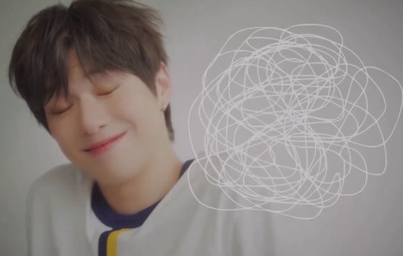 Kang Daniel smiling with closed eyes, maintaining positive energy post robbery in Los Angeles.