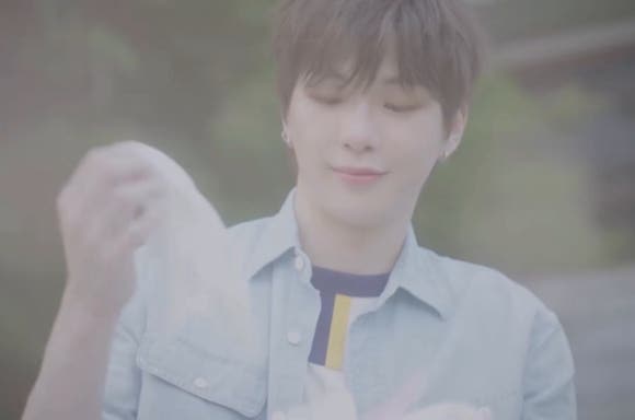 Kang Daniel smiling gently while holding a handkerchief, reflecting resilience after robbery in Los Angeles.