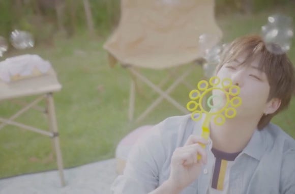Kang Daniel blowing bubbles peacefully during picnic despite Kang Daniel robbery in Los Angeles incident.