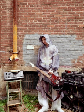 CORTIS debut album sales concept photo member holding guitar in urban alley