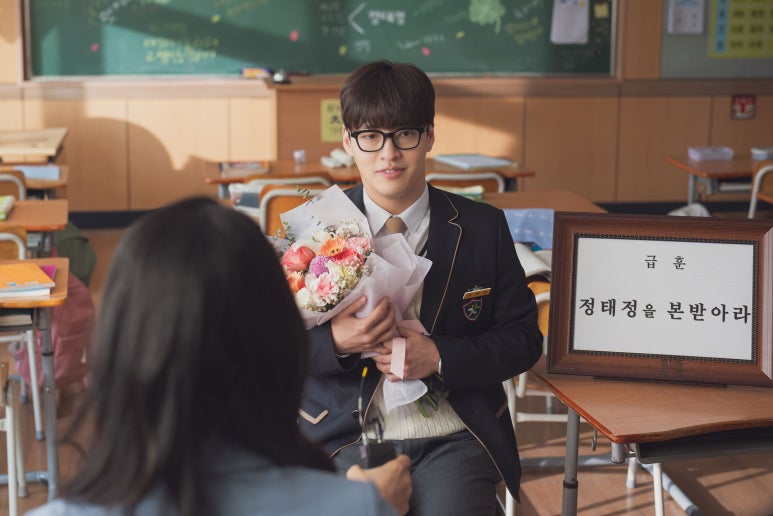 Kang Ha Neul as Tae Jeong holding flowers in a school setting scene from The First Ride
