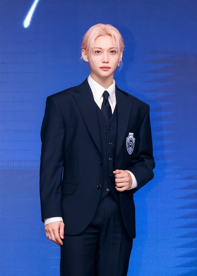 Stray Kids member in suit at press event celebrating Billboard 200 record