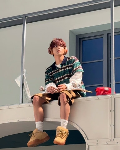 NCT DREAM Beat It Up teaser rooftop concept with member in striped shirt and headphones, sitting next to skateboard