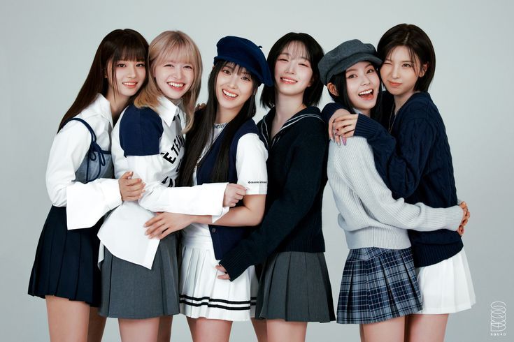 Nmixx Blue Valentine members in navy school-style outfits, smiling brightly in group pose