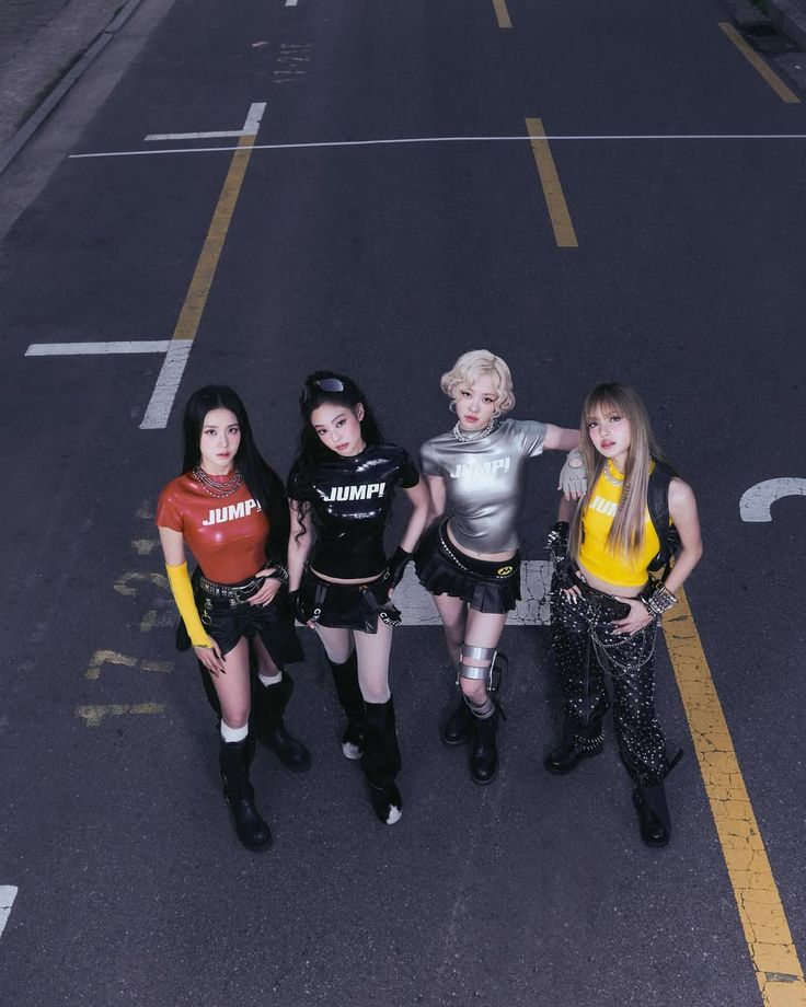 Top-down view of a K-pop girl group posing in formation on an urban street in colorful cyberpunk-inspired outfits with high boots and accessories