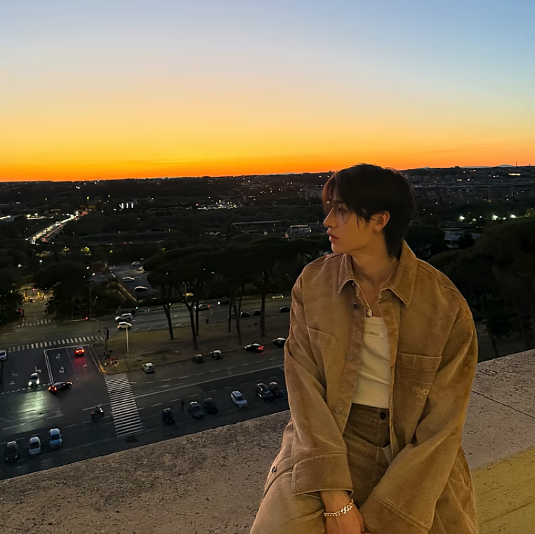 Hyunjin of Stray Kids gazes into the sunset in Rome, wearing a soft suede jacket – travel photo capturing golden hour.