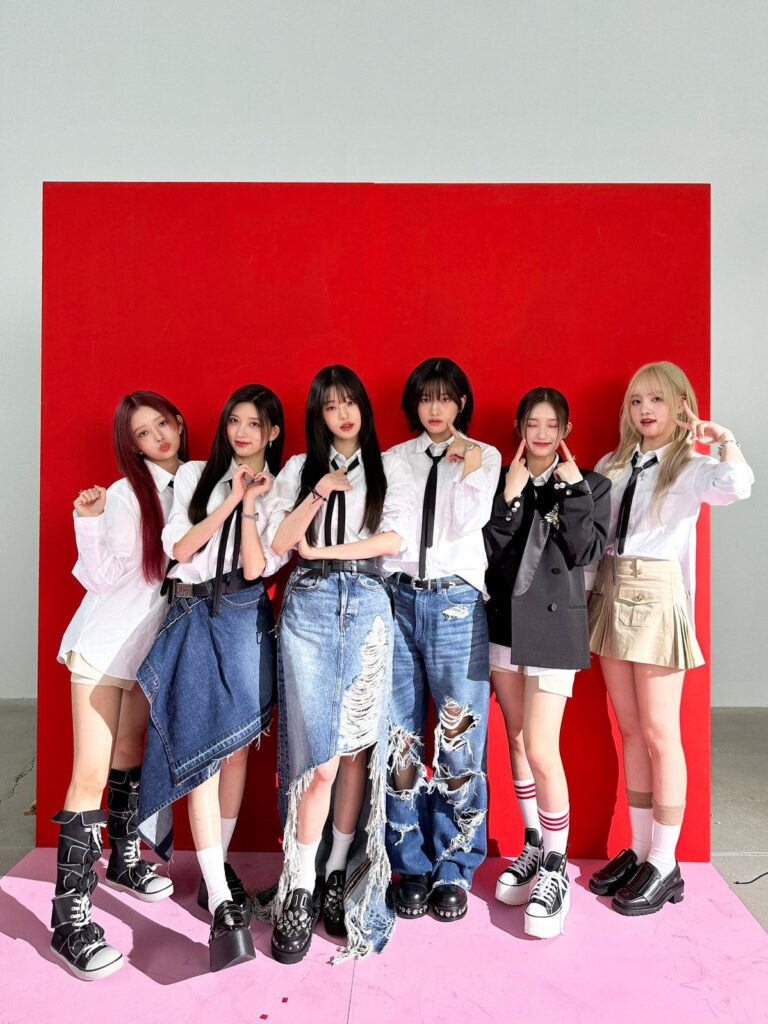 Nmixx posing in front of red backdrop with unique denim fashion for Blue Valentine