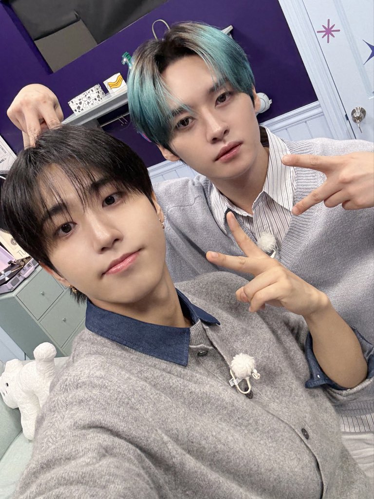 Stray Kids members Seungmin and Hyunjin take a cute selfie together wearing cozy sweaters on a TV recording set.