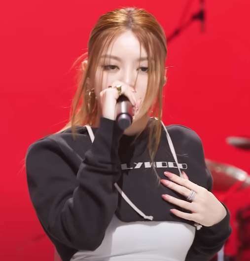 ALLDAY PROJECT rapper performing in a cropped hoodie on a red stage — ALLDAY PROJECT comeback showcase rehearsal