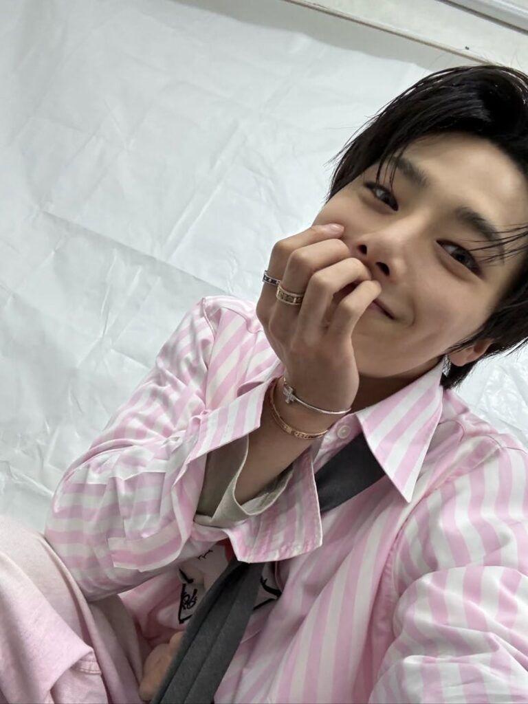Stray Kids Hyunjin takes a playful selfie in pink striped shirt, showing rings and bracelets – 2025 KGMA behind the scenes.