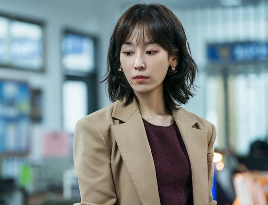 Seo Hyun-jin as Seo Jun-kyung in Love Me, wearing a tan blazer inside a hospital office setting