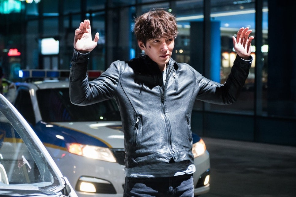 Main character raising hands during police arrest in Fabricated City film
