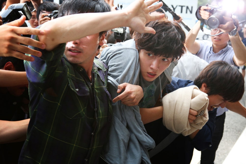 Chaotic media scene with protagonist surrounded by reporters in Fabricated City movie