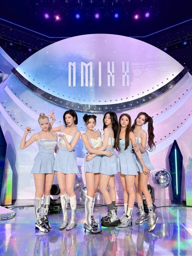 Nmixx group photo on Blue Valentine stage with shimmering lights and silver tones