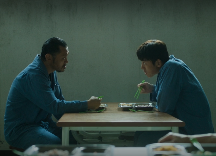 Prison cafeteria scene with two inmates talking in “Bad Prosecutor” K-drama