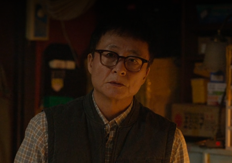 Elderly man with glasses in a dark room from Korean drama “Bad Prosecutor”