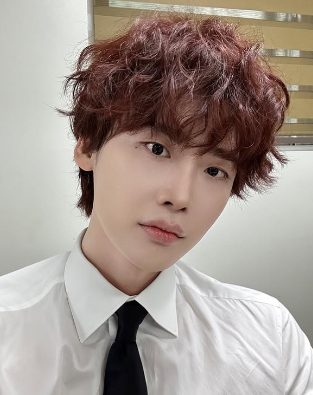 Lee Jong Suk with curly brown hair and white shirt — formal look following his canceled fanmeeting announcement