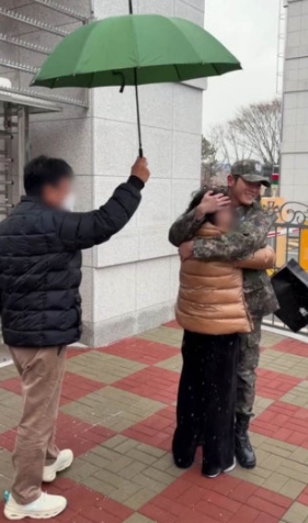 Taeyong military discharge moment hugging a loved one under an umbrella outside Navy base