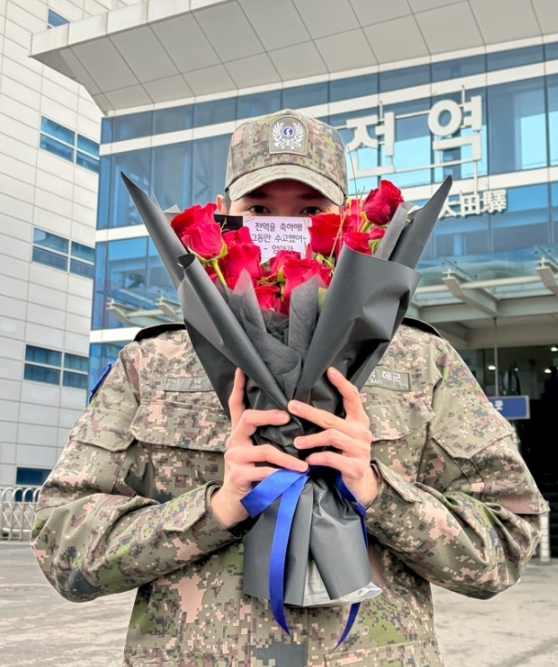 Taeyong hides behind red roses in uniform, celebrating military discharge at Daejeon Station