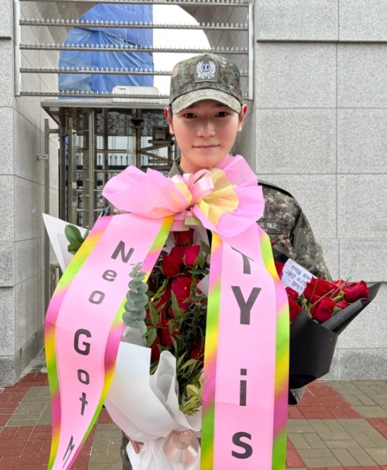 Taeyong holding rose bouquets and pink ribbon reading TY is BACK after military discharge