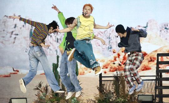 CORTIS members mid-jump during a live performance, showcasing their electrifying choreography at their K-pop debut.